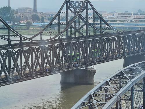 Photo prise le 16 août 2023 montrant des autocars traversant un pont reliant la ville frontalière nord-coréenne de Sinuiju à la ville chinoise de Dandong.