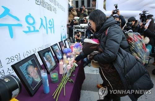 今年亡くなった慰安婦被害者の遺影に献花する集会参加者＝２８日、ソウル（聯合ニュース）