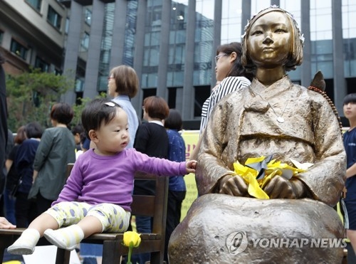 今月６日、日本大使館前で開かれた水曜集会に参加した子どもと少女像＝（聯合ニュース）
