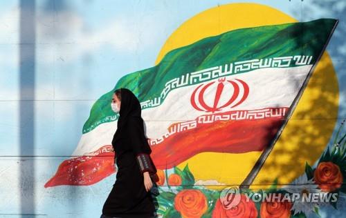 イランの国旗の前を通り過ぎるテヘラン市民（資料写真）＝（ＥＰＡ＝聯合ニュース）