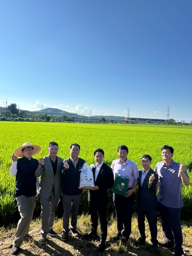 坡州市の田んぼの前で記念撮影する小泉氏（中央）と関係者（読者提供）＝（聯合ニュース）≪転載・転用禁止≫