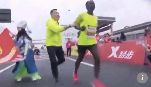 중국 마라톤 대회 우승자의 팔을 잡아끄는 대회 관계자