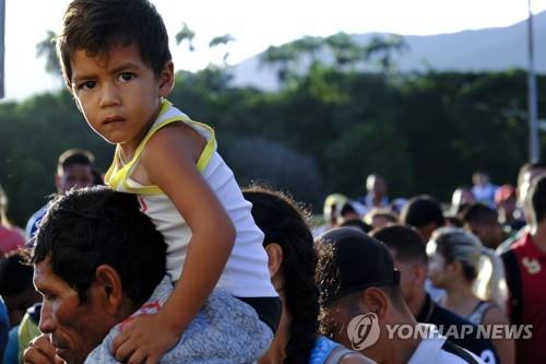 아이를 어깨에 태운 채 콜롬비아 국경으로 온 베네수엘라인