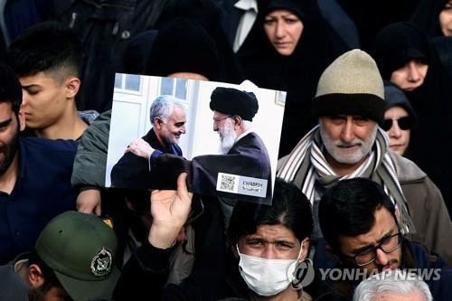 솔레이마니 사령관과 아야톨라 하메네이의 사진을 들고 있는 이란 시민