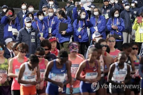 (도쿄 EPA=연합뉴스) 1일 일본 도쿄에서 14회 도쿄마라톤 대회가 열린 가운데 대회 스태프들이 마스크를 쓰고 선수들을 지켜보고 있다. 2020.3.4