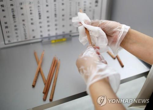 (도쿄 로이터=연합뉴스) 5일 실시된 일본 도쿄도(東京都) 지사 선거 투표장에서 선관위 관계자가 후보자의 이름을 쓸 때 사용할 연필을 소독하고 있다. 