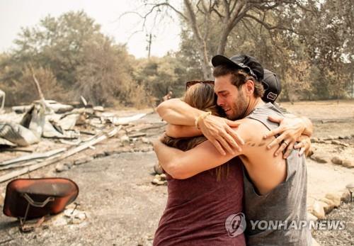 23일(현지시간) 미 캘리포니아주 배커빌의 한 주민이 LNU 파이어로 불타고 잔해만 남은 집 앞에서 가족들을 안은 채 울고 있다. [AFP=연합뉴스]