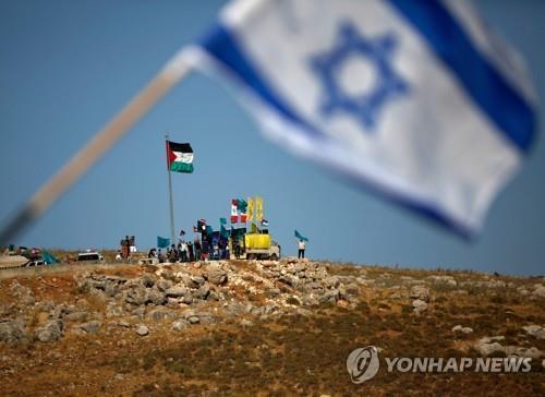 이스라엘 북부 국경에 내걸린 이스라엘 국기 뒤로 레바논에서 레바논 국기와 팔레스타인, 헤즈볼라 깃발을 세우고 반이스라엘 시위를 벌이는 사람들. [AFP=연합뉴스 자료사진]