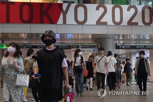 (도쿄 AFP=연합뉴스) 27일 도쿄 올림픽 홍보 간판이 설치된 일본 도쿄도(東京都)의 한 역에서 마스크를 쓴 사람들이 이동하고 있다.
