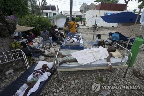 아이티 레카이 병원 밖 임시 침대에서 치료를 기다리는 부상자들