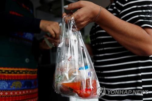 비닐봉지로 쌓인 음식물이 담긴 비닐봉지를 들고 가는 태국 시민