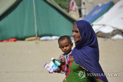 파키스탄 이재민 구호 시설에서 아이와 약을 들고 이동하는 여성.