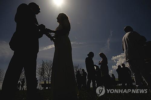 개기일식에 맞춰 열린 대규모 합동 결혼식에서 결혼반지를 교환하는 신랑신부들