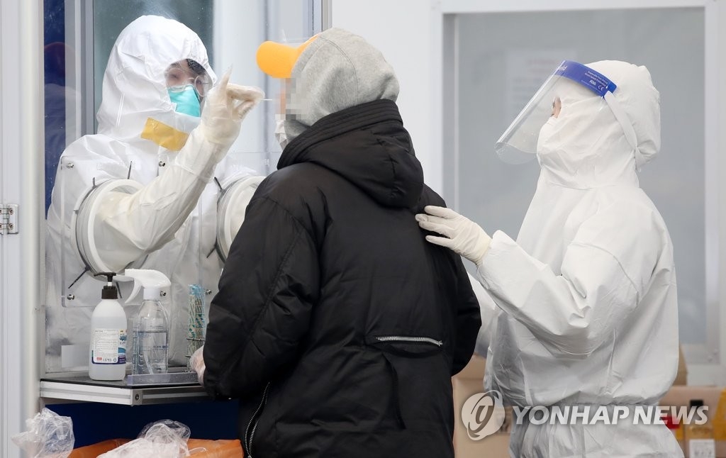 La foto de archivo muestra a los trabajadores médicos llevando a cabo una prueba del COVID-19 a un ciudadano, en una clínica provisional, en Seúl.