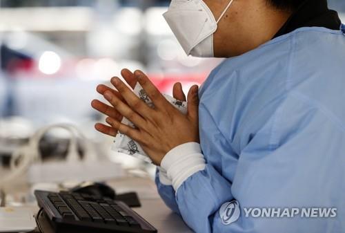 Una trabajadora médica se calienta las manos con una bolsa térmica instantánea, el 17 de octubre de 2021, en una clínica provisional de exámenes de COVID-19 en Seúl, en medio de una ola de frío a nivel nacional.