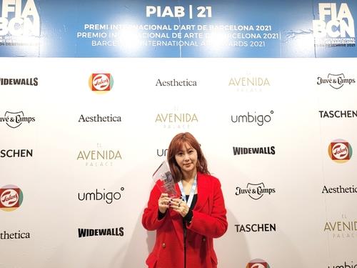 La foto, proporcionada, el 6 de diciembre de 2021, por M.A.P. Crew, muestra a SolBi posando con su trofeo en los Premios Internacionales de Arte de Barcelona, en España. (Prohibida su reventa y archivo)