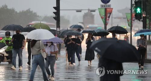 El 23 de junio de 2022, las personas con paraguas cruzan una calle bajo la lluvia, en la intersección de Gwanghwamun, en Seúl.