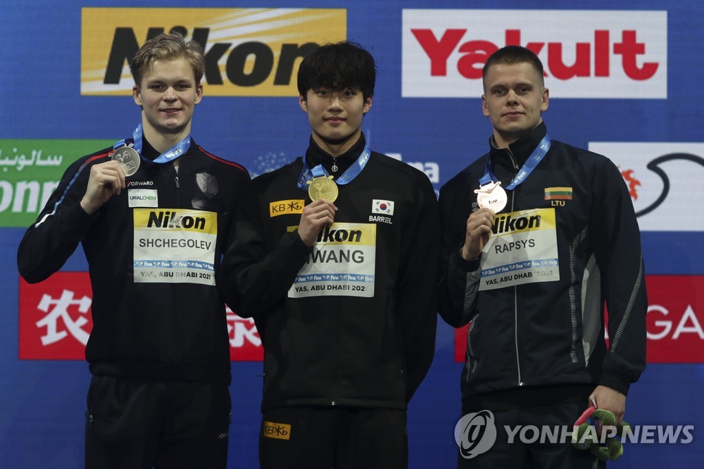 In this AP photo, South Korean Hwang Sun-woo (C) stands at the podium with Aleksandr Shchegolev of Russia (L) and Danas Rapsys of Lithuania (R) after the 200-meter freestyle during the FINA World Short Course Swimming Championships in Abu Dhabi, United Arab Emirates, on Dec. 17, 2021. (Yonhap)