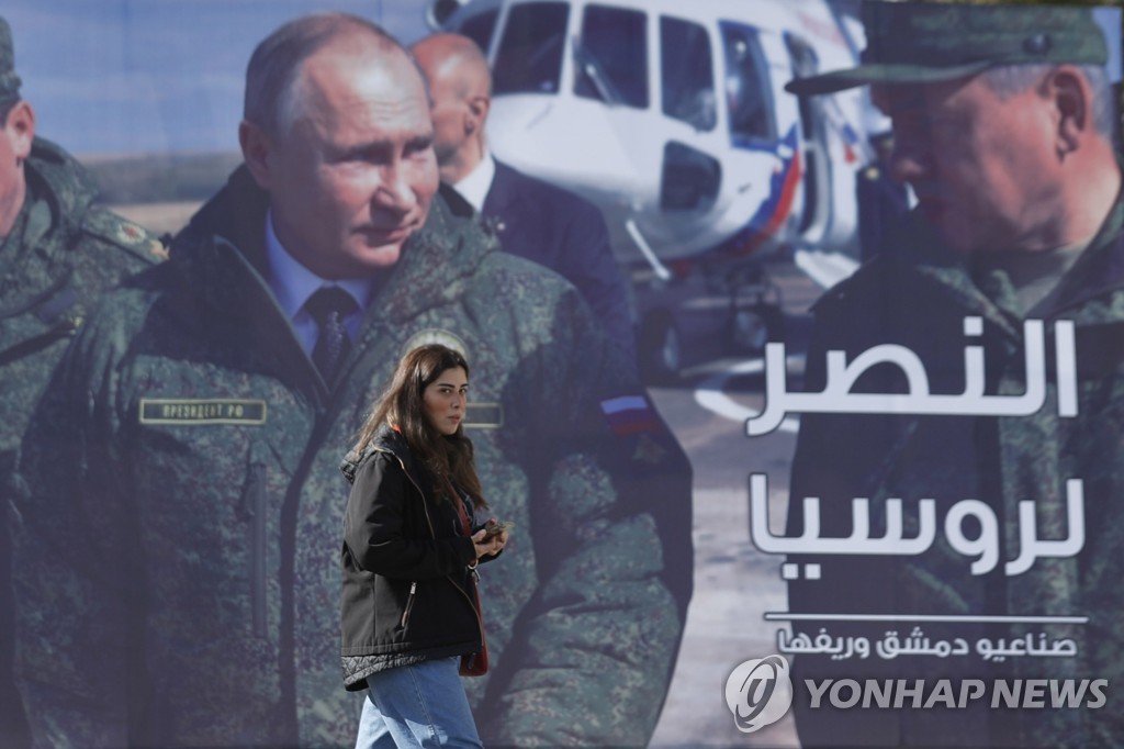 시리아 다마스쿠스에서 블라디미르 푸틴 러시아 대통령의 모습이 담긴 광고판 앞을 한 시민이 지나고 있다.