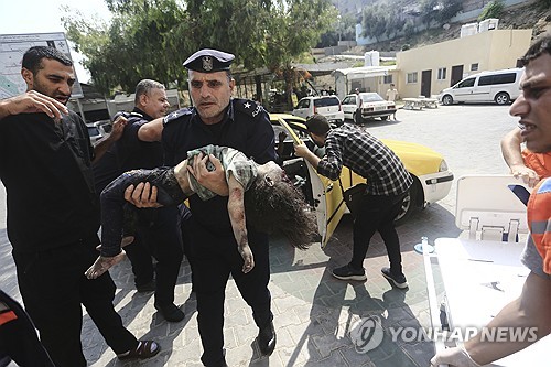 지난 8일(현지시간) 팔레스타인 가자지구에서 하마스 경찰관이 부상한 한 여자아이를 병원으로 데려가고 있다. [AP  자료사진]