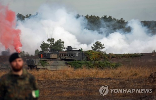 훈련 중인 레오파드2 전차 옆에 선 독일군 병사의 모습