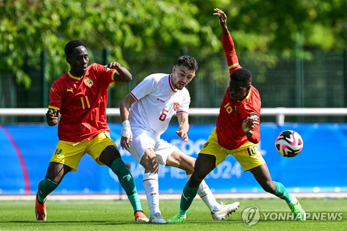 In this AFP photo, Ivar Jenner of Indonesia (C) is surrounded by Ousmane Camara (L) and Aguibou Camara of Guinea during the teams' Olympic qualifying playoff match at INF Clairefontaine in Clairefontaine-en-Yvelines, France, on May 9, 2024. (Yonhap)