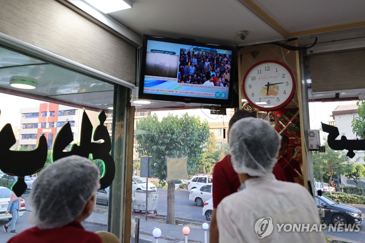 (테헤란 AFP=연합뉴스) 20일(현지시간) 이란 테헤란의 한 식당 직원들이 라이시 대통령 사망 속보를 TV로 지켜보고 있다. 2024.5.20