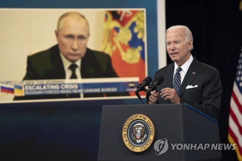 블라디미르 푸틴 러시아 대통령의 얼굴을 배경으로 발언하는 조 바이든 미 대통령