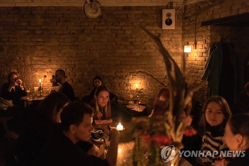 러시아의 전력망 공습으로 전기 공급이 끊긴 우크라이나 수도 키이우에서 지난달 6일 촛불을 켠 식당에서 손님들이 식사하는 모습