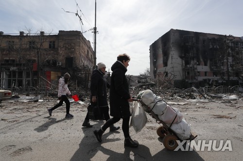 10일(현지시간) 우크라이나 남부 마리우폴에서 파괴된 건물 부근을 지나가는 주민들[신화=연합뉴스 자료사진]
