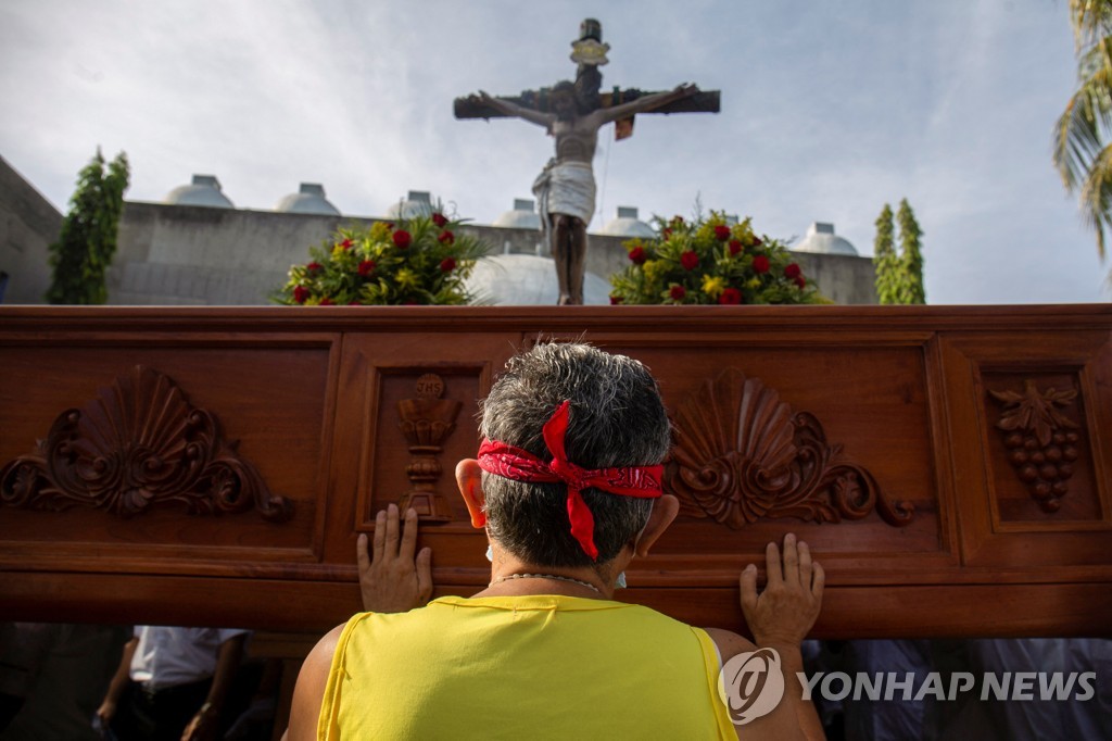 십자가상 아래에서 기도하는 니카라과 가톨릭 신자