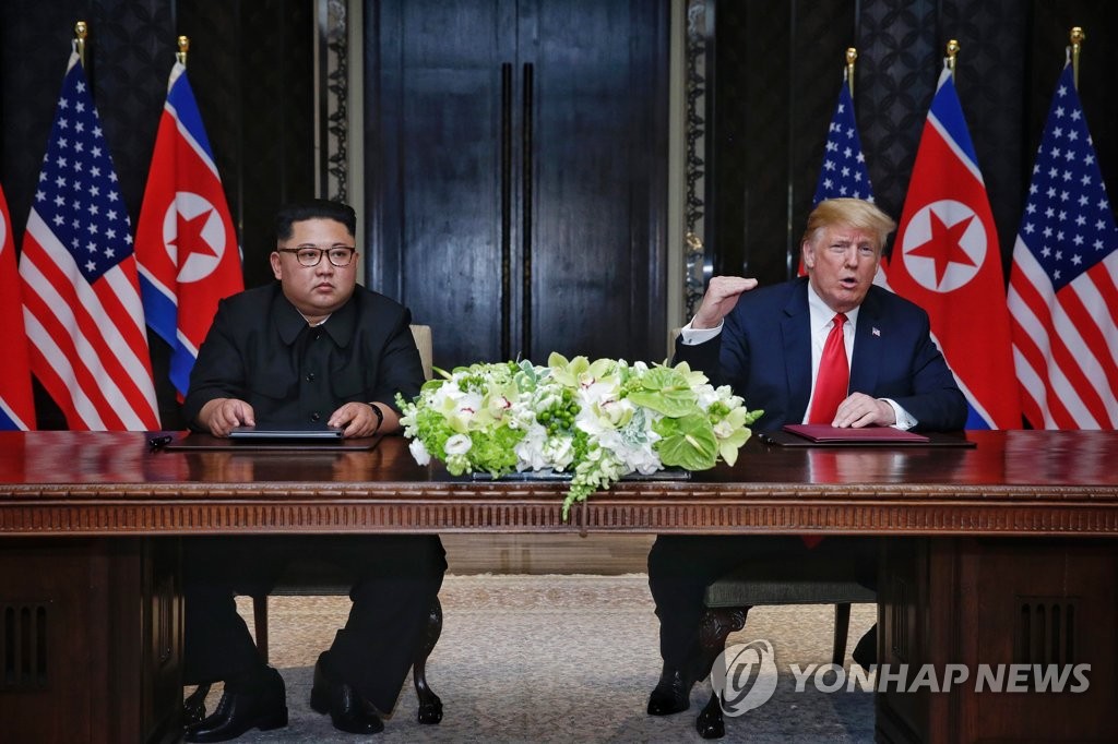 This photo, provided by the Singaporean government, shows North Korean leader Kim Jong-un (L) and U.S. President Donald Trump at the signing of a joint statement following their summit in Singapore on June 12, 2018. (Yonhap)