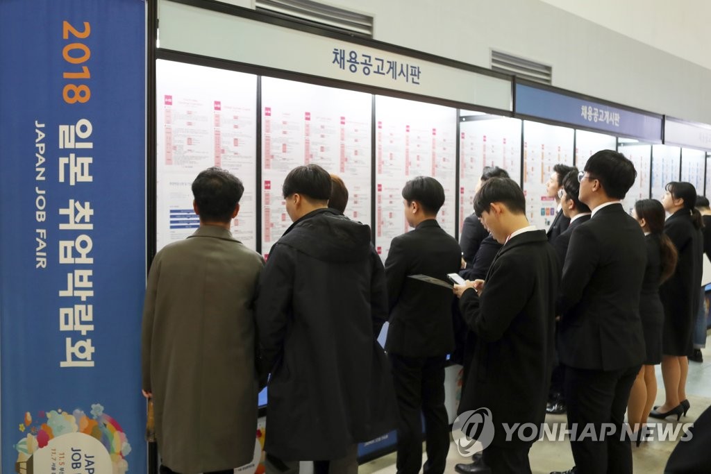 会場の入口に置かれた掲示板の前で日本企業の採用情報を集める韓国の求職者＝（聯合ニュース）
