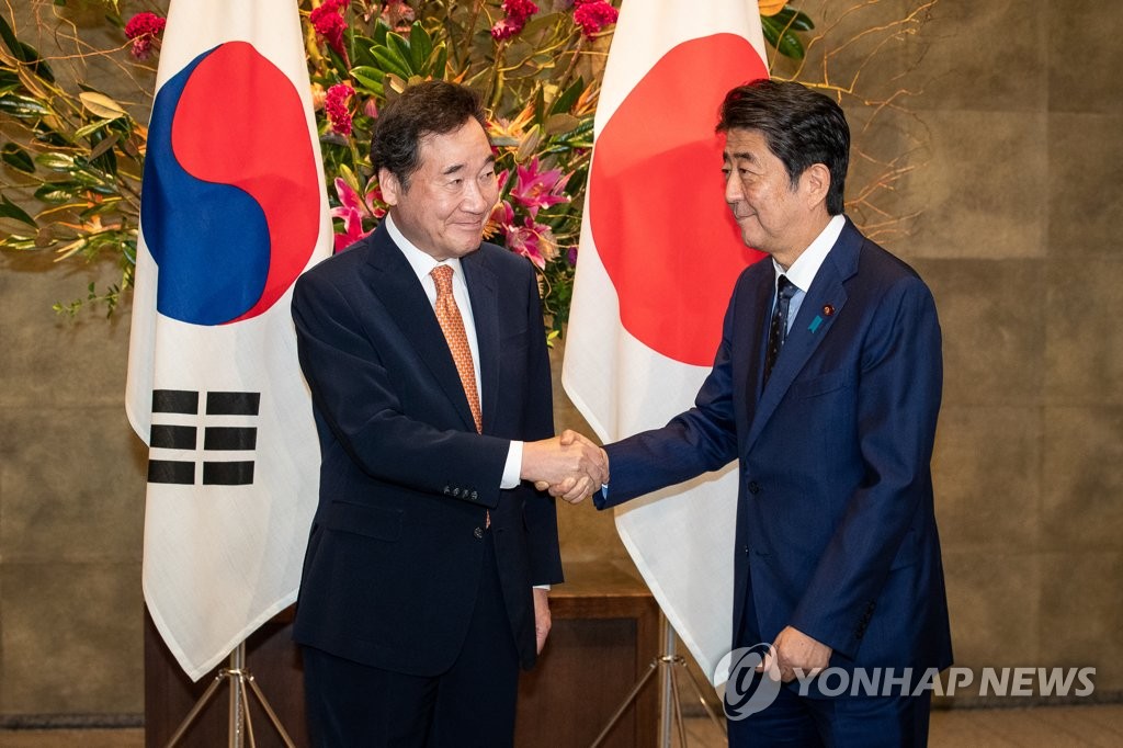 握手を交わす李首相（左）と安倍首相＝２４日、東京（聯合ニュース）