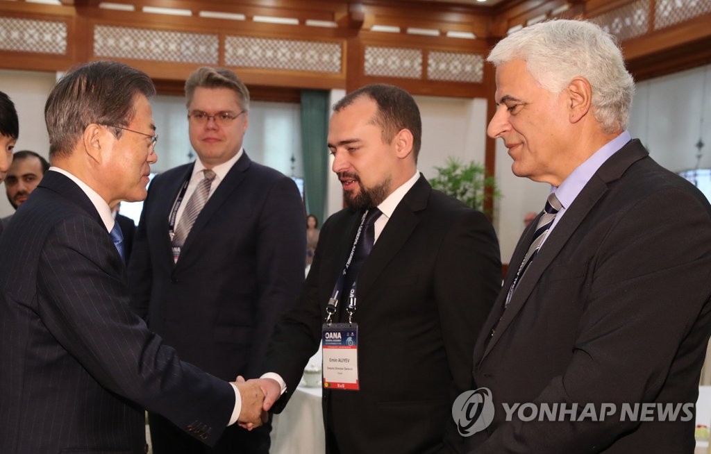 President Moon Jae-in (L) greets delegates attending the 17th Organization of Asia-Pacific News Agencies (OANA) General Assembly at a meeting at Cheong Wa Dae in Seoul on Nov. 7, 2019. (Yonhap)