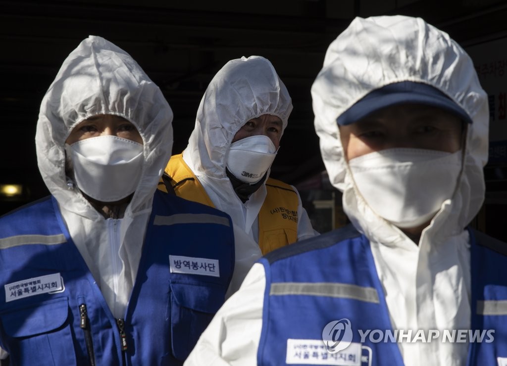 Volunteer workers carry out a disinfection operation at a market located in western Seoul on Feb. 5, 2020. (Yonhap)