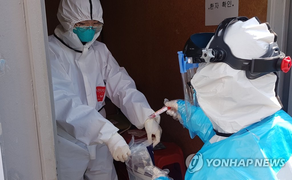 Medical personnel at Yeungnam University Medical Center in Daegu, 300 kilometers southeast of Seoul, seal samples collected from people through the hospital's drive-thru testing process on March 5, 2020. (Yonhap)
