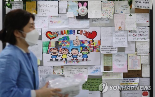 A medical staff member walks past a wall in a corridor at Dongsan Hospital in Daegu on March 9, 2020. The wall is decorated with various messages to cheer up virus patients and medical staff. (Yonhap)