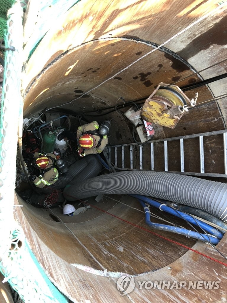 Rescue staff work to pull out three Chinese-Korean workers trapped inside a manhole the southeastern city of Busan on April 9, 2020, in this photo provided by the local fire service. All of them died after being taken to a hospital. (PHOTO NOT FOR SALE) (Yonhap)