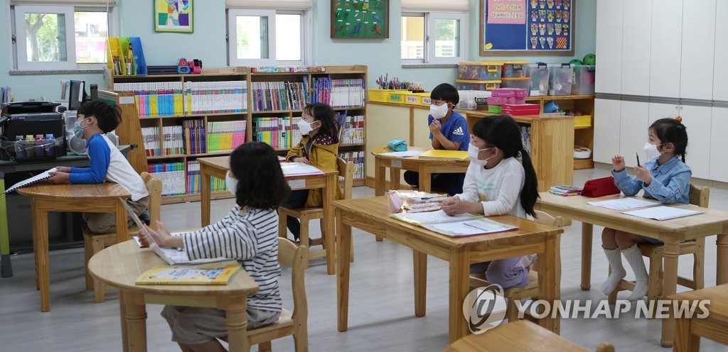 Mask-wearing students at an elementary school in the southern city of Gimhae take part in an emergency childcare class on May 6, 2020. (Yonhap)