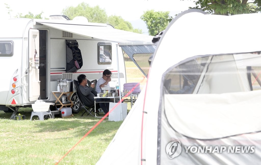 In front of a camping van, citizens relax at a camping ground in Haman County, South Gyeongsang Province, on May 12, 2020. (Yonhap)