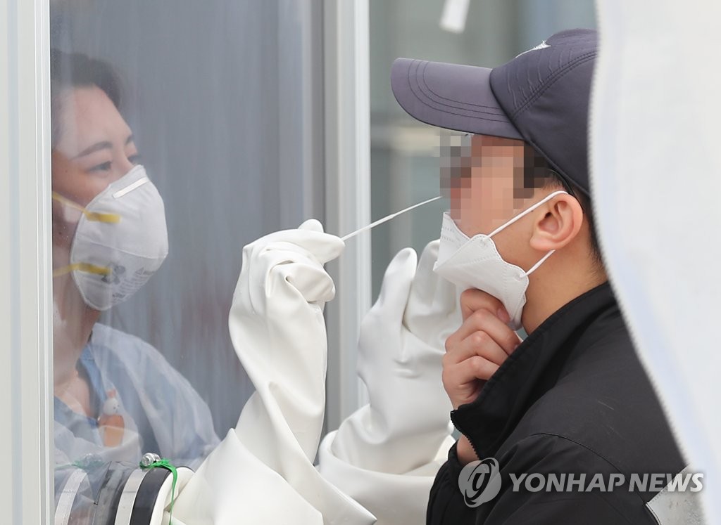 A health worker collects sample from a police for the novel coronavirus test at the National Medical Center in Seoul on May 13, 2020. (Yonhap)