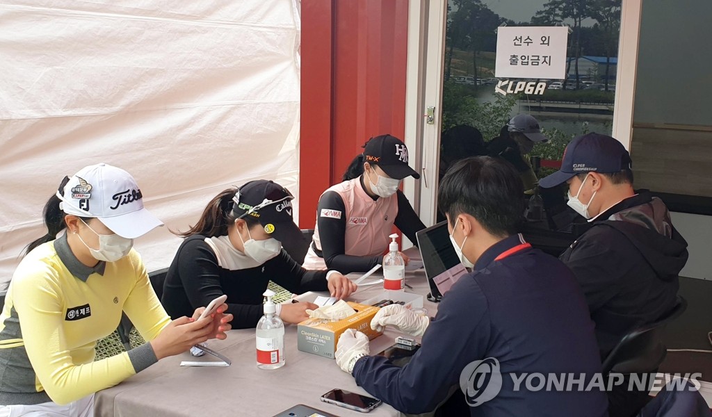 Players sign their scorecards inside the scoring tent, with bottles of hand sanitizer on the table, after the first round of the 42nd Korea Ladies Professional Golf Association (KLPGA) Championship at Lakewood Country Club in Yangju, Gyeonggi Province, on May 14, 2020. (Yonhap)