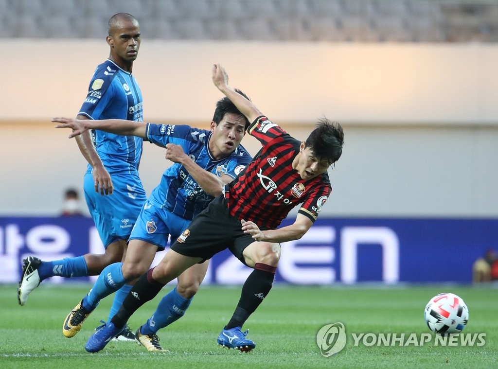 Jung Hoon-sung of Ulsan Hyundai FC (C) and Ju Se-jong of FC Seoul (R) battle for the loose ball during their K League 1 match at Seoul World Cup Stadium in Seoul on June 20, 2020. (Yonhap)