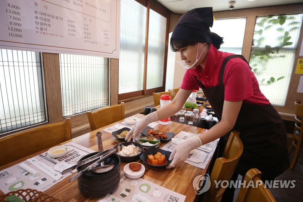 A staff member wearing a protective mask serves dishes at a restaurant in Gwangju, 330 kilometers south of Seoul, in this file photo taken on July 21, 2020. (Yonhap)