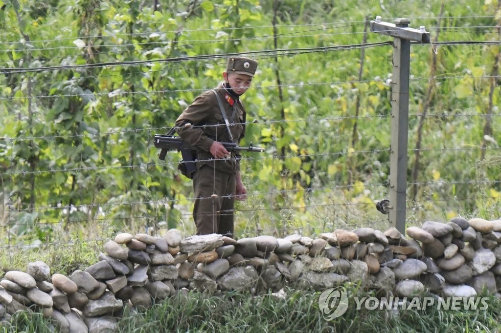今月初め、中国・吉林省長白朝鮮族自治県から撮影した北朝鮮側。銃を持った朝鮮人民軍の兵士が鴨緑江沿いを警備している（資料写真）＝（共同＝聯合ニュース）