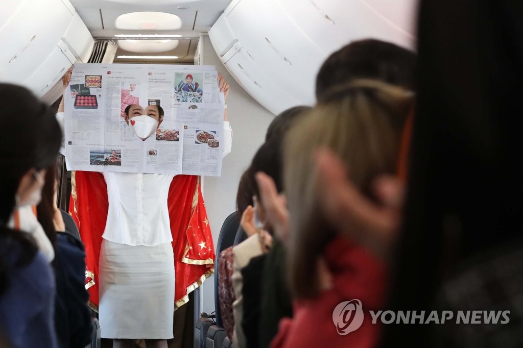 This photo, provided by the Incheon International Airport press pool, shows a flight attendant performing magic aboard a Jeju Air flight to nowhere on Oct. 23, 2020. (Yonhap)
