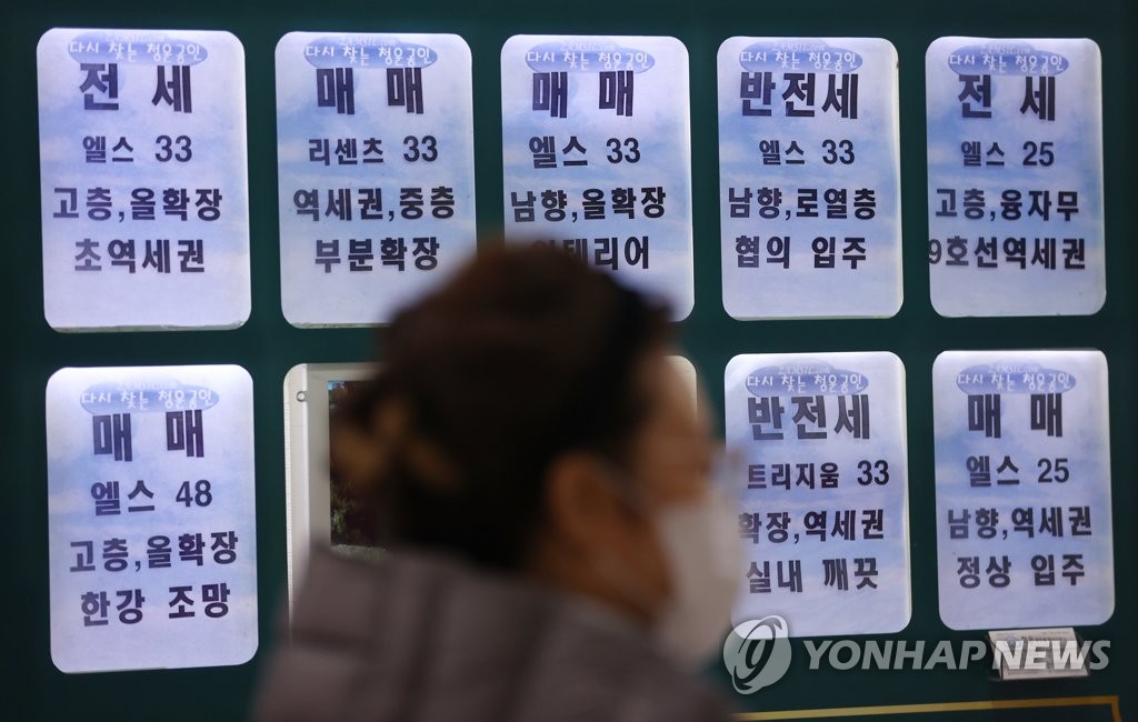 This photo, taken on Nov. 18, 2020, shows a citizen walking past a real estate office with the sale and rental prices of apartments in Songpa, eastern Seoul. (Yonhap)