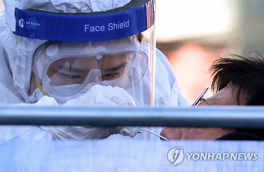 A medical worker carries out COVID-19 tests on visitors at a makeshift clinic in central Seoul on Dec. 16, 2020. (Yonhap)