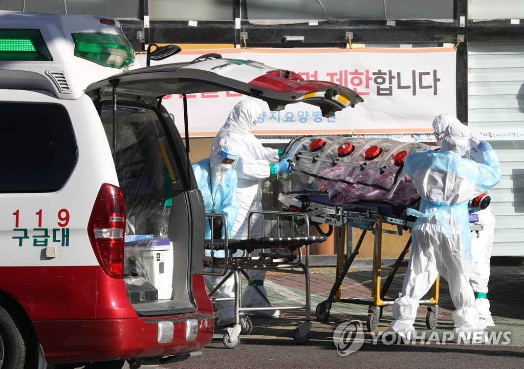 Medical workers clad in protective gear carry a patient infected with the new coronavirus onto an ambulance at an elderly care facility in the southeastern city of Ulsan on Dec. 17, 2020, following the discovery the same day of 18 more people infected with the virus there. The number of coronavirus cases linked to the facility has so far climbed to 226. (Yonhap)